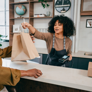 Small business owner handing a bag to a customer, representing great customer service and local business growth.